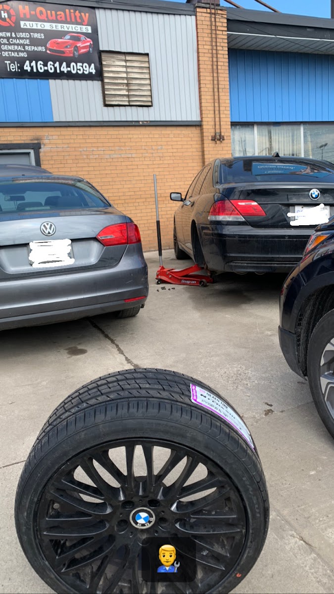 Two cars parked outside the shop with a fresh black BMW wheel and tire in the foreground.